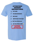 A light blue short-sleeve t-shirt shown from the back, featuring a humorous checklist titled 'ATTENTION! DOCKING INSTRUCTIONS:' in black text, with a red 'CAPTAIN APPROVED' stamp graphic at the bottom.