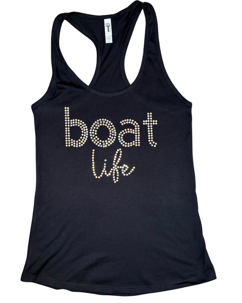 Black women's racerback tank top featuring the phrase "boat life" in sparkling rhinestone lettering. The word "boat" is displayed in lowercase block letters, with "life" in a cursive script beneath it. The tank top is laid flat on a black-and-gray checkered background.