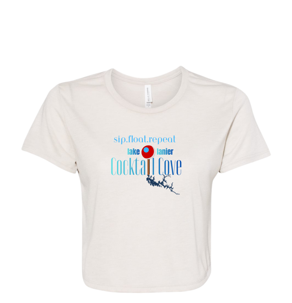 An off-white short-sleeve crewneck t-shirt with a graphic print on the front. The graphic features the text 'sip,float,repeat', 'lake lanier', and 'Cocktail Cove' in blue and red, along with an illustration of Lake Lanier and a pin showing the location of the cove