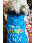 A small dog viewed from behind wearing a bright blue pet shirt with the text 'I'm so DOGGONE Cute' in white.