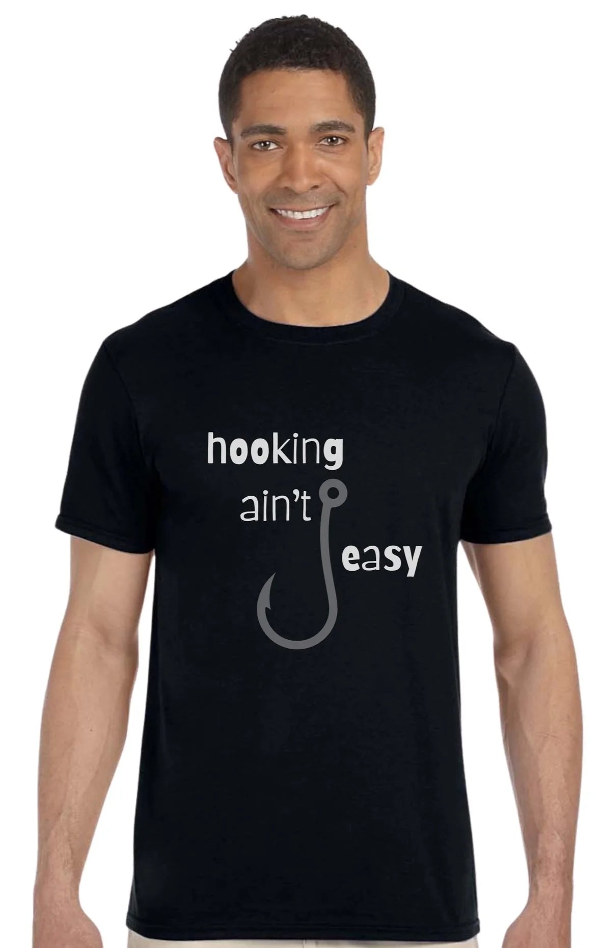 A man wearing a black short-sleeve t-shirt with a white and gray graphic that reads 'hooking ain't easy' with a fishing hook illustration, set against a plain white background.