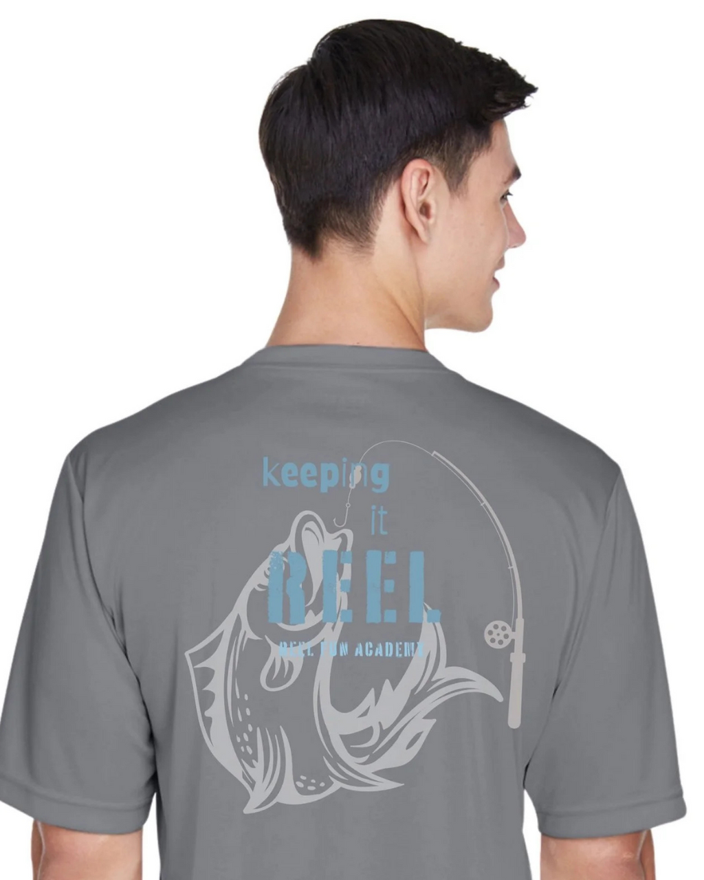 A man shown from the back wearing a gray t-shirt with a light blue and white graphic that reads 'keeping it REEL FISHING ACADEMY' with a fish and fishing rod design.