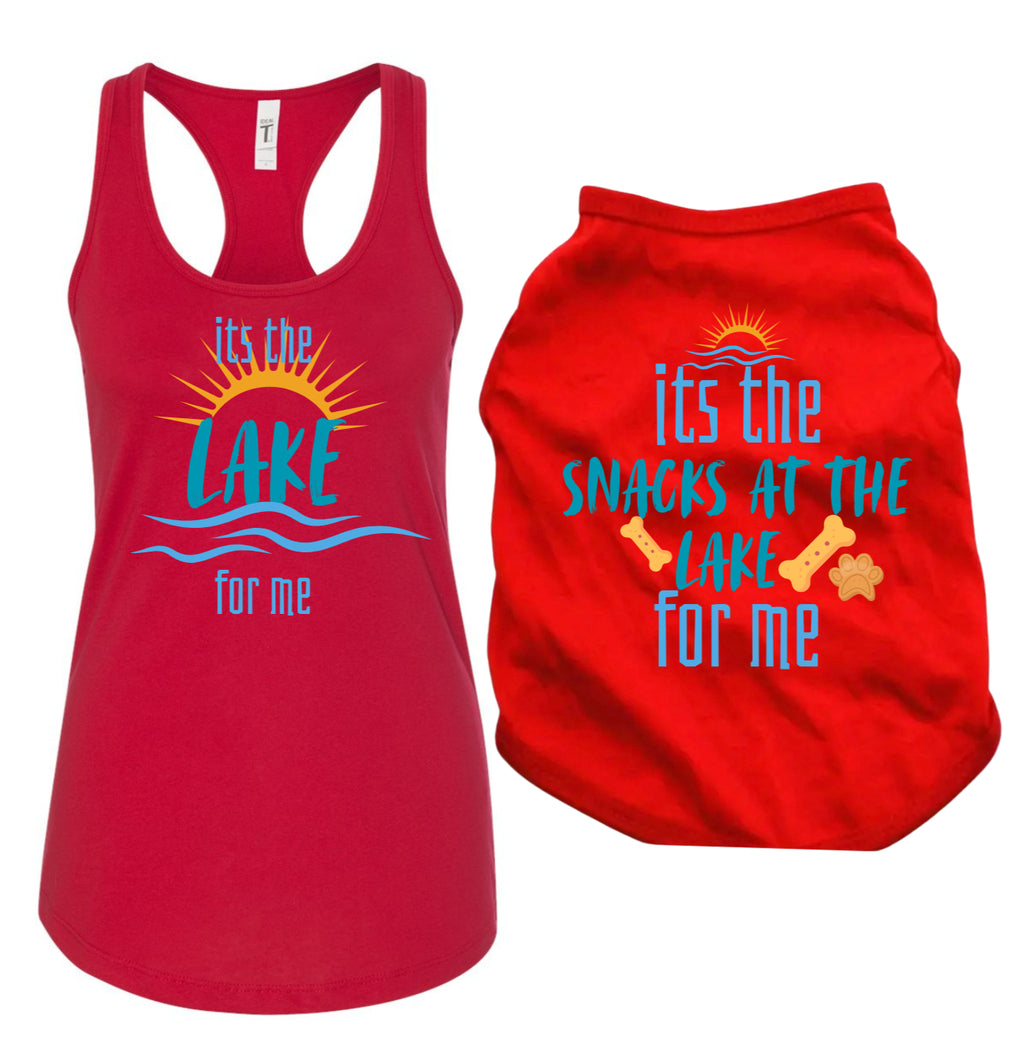 A matching pet apparel set consisting of a red racerback tank top and a red pet tee, both featuring a blue and yellow graphic. Dog reads 'its the LAKE snacks at the LAKE for me' with a sun, waves, and bone illustrations, tank reads "it's the lake for me" shown on a plain white background.