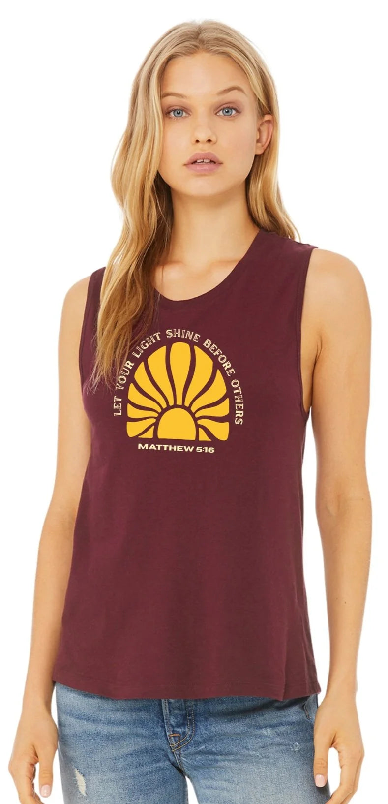 A blonde woman wearing a burgundy sleeveless crop top with a yellow sun graphic and white words that read "Let your light shine before others" Matthew 5:16 graphic on the front, set against a plain white background.