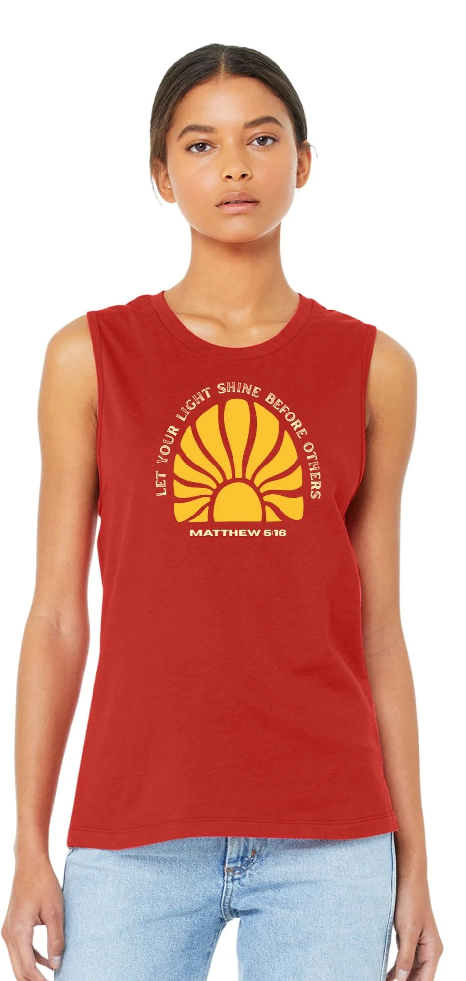 A woman modeling a sleeveless red tank top with a yellow and white Shell logo and 'Let Your Light Shine Before Others' text, paired with light blue jeans against a white background.