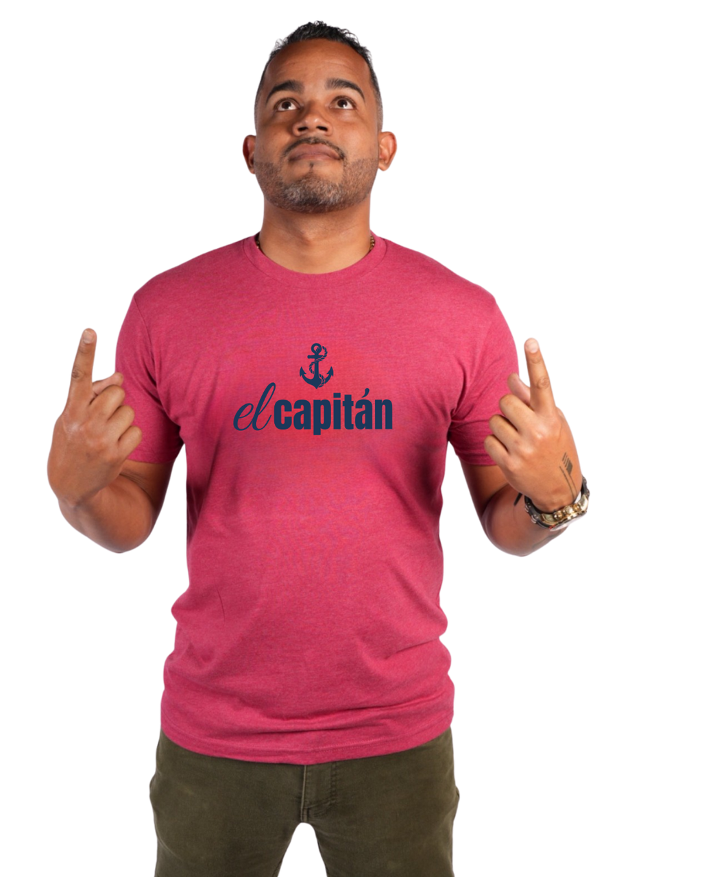 A man wearing a heathered pink t-shirt with a navy blue graphic that reads 'el capitán' with an anchor icon, posing with his hands raised against a plain white background.