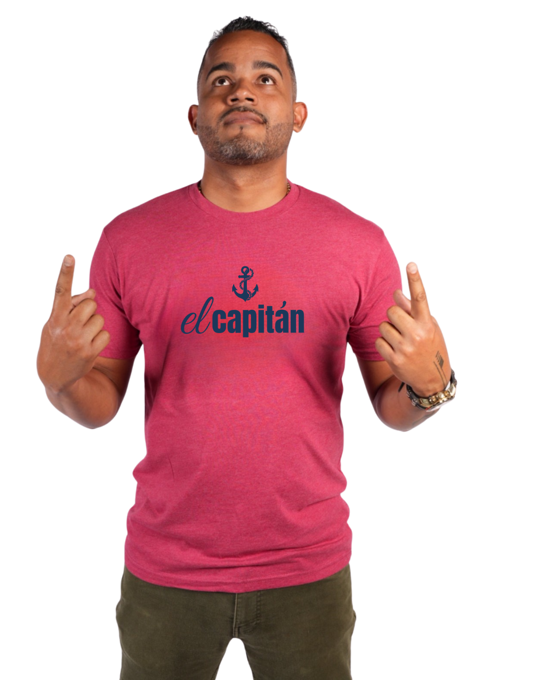 A man wearing a heathered pink t-shirt with a navy blue graphic that reads 'el capitán' with an anchor icon, posing with his hands raised against a plain white background.