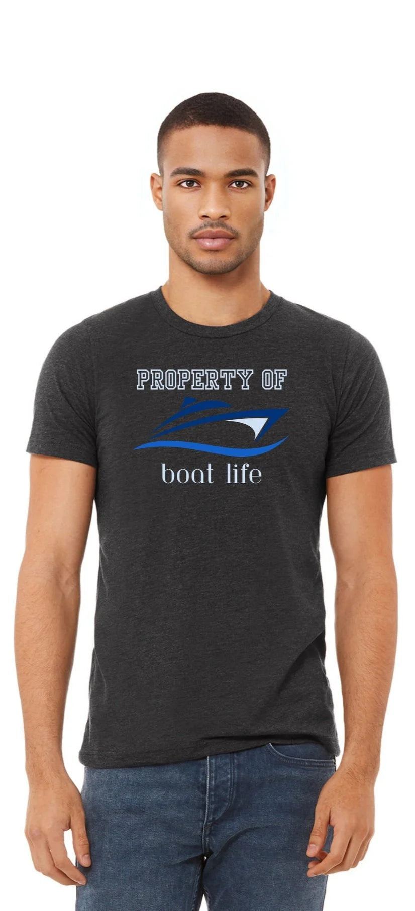 A man wearing a dark heather gray t-shirt with a blue and white boat graphic that reads 'PROPERTY OF boat life' and a wave design, paired with blue jeans, against a plain white background.